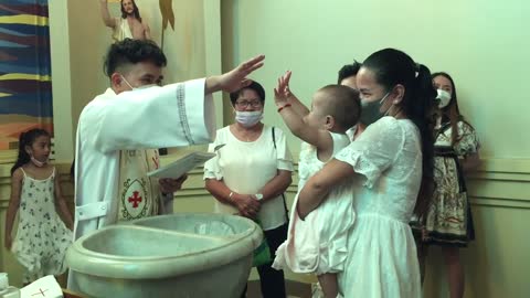 Cute little baby high fives Father while being baptized