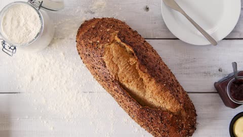 Top View Hand Putting Down Seeded Bread on Table