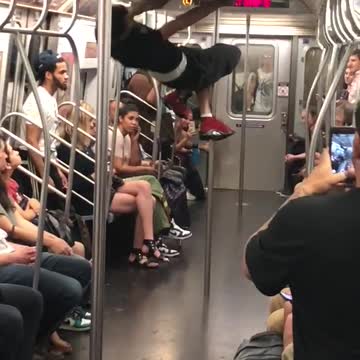 A man in a black shirt jumping and swinging from train