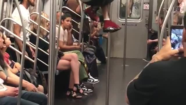 A man in a black shirt jumping and swinging from train