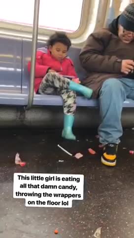 Little girl in pink jacket eating candy with wrappers on floor