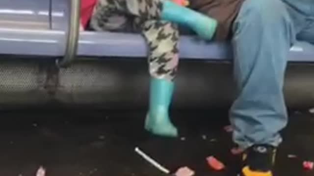 Little girl in pink jacket eating candy with wrappers on floor