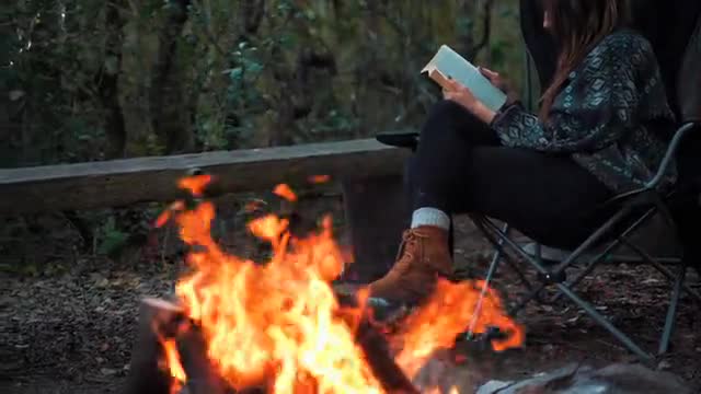 a woman reading a book while camping
