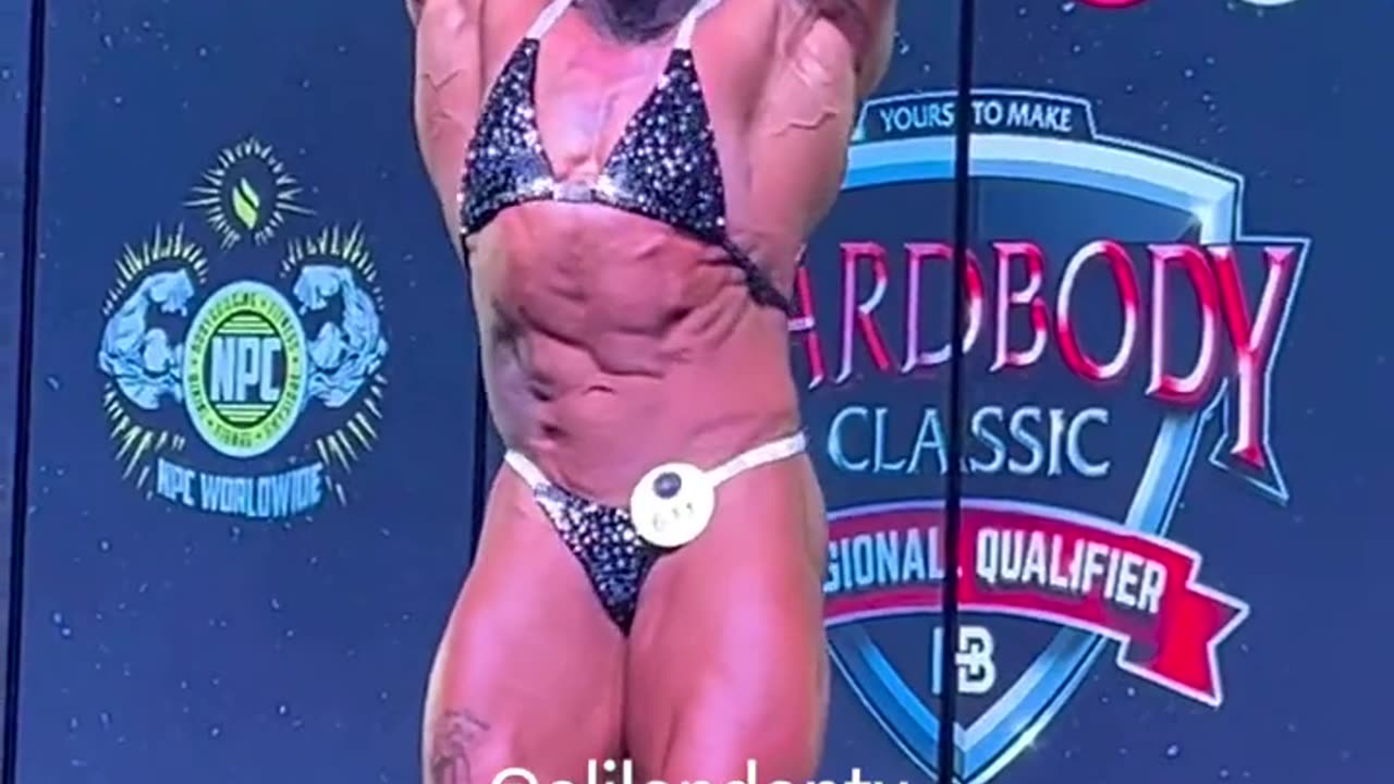 Biological MAN dressed in a bikini and thong competes in women’s bodybuilding competition