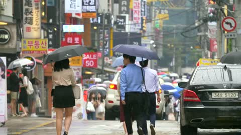 People Walking Down Wet Seoul Street