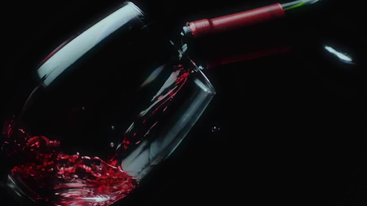Leaning glass on a black background filled with red wine