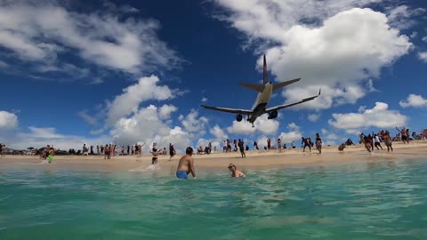 Airplane Passing Close to a Beach as a Guy Swims