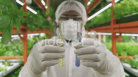 Young Contemporary Researcher Or Agroengineer In Protective Workwear Holding Two Flasks With Liquid