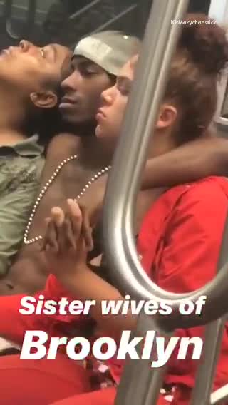 Man has arms around two women sitting on train