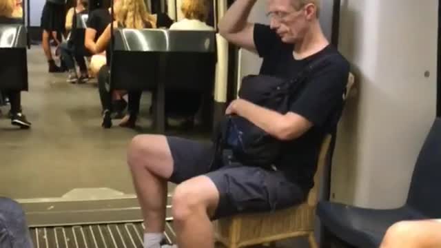 Man black shirt brings own wooden chair on subway