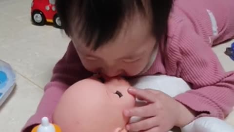 The baby is playing with a doll