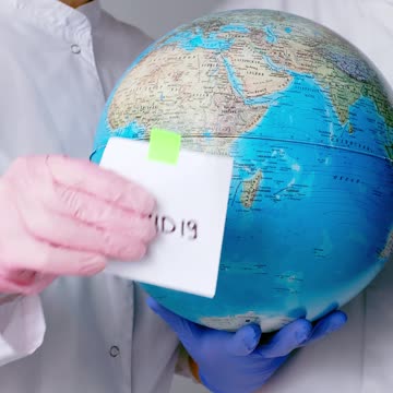 People With Face Masks and Latex Gloves Holding a Globe Uploaded at April 17, 2020