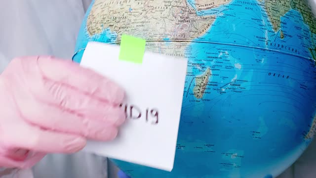 People With Face Masks and Latex Gloves Holding a Globe Uploaded at April 17, 2020