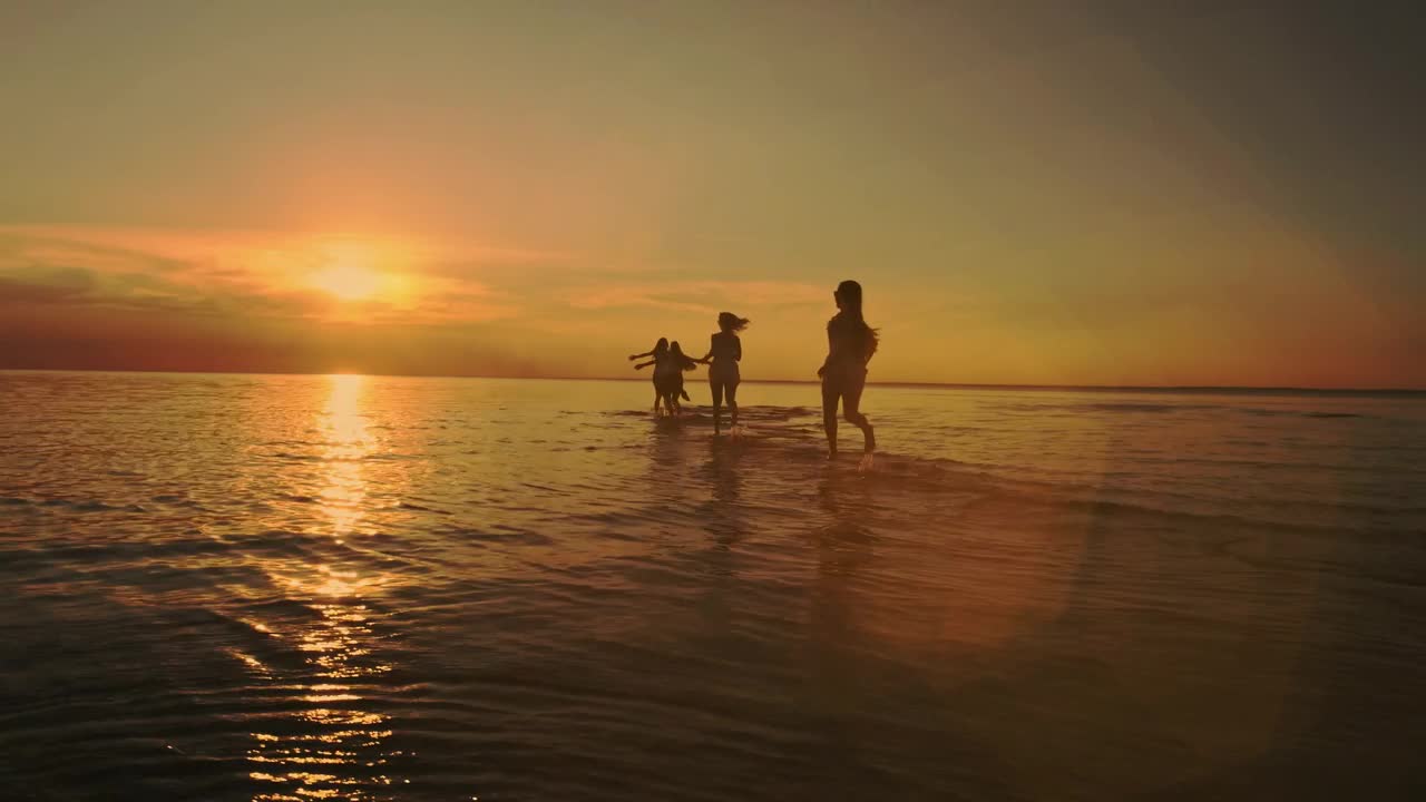 Friends running on the beach towards the sea