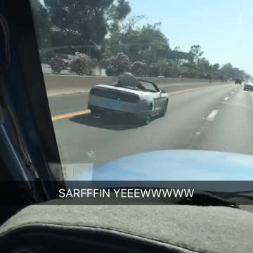 Red surfboard in silver car on freeway