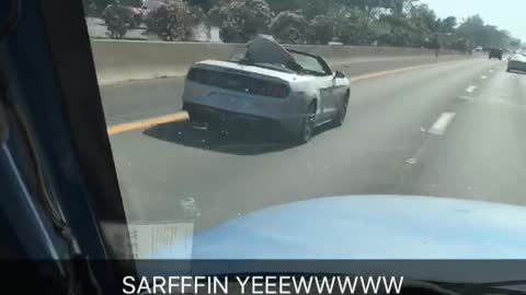 Red surfboard in silver car on freeway