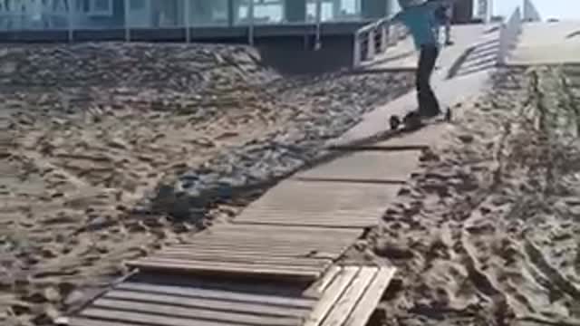 Guy longboard skateboard down wood pier sand falls over