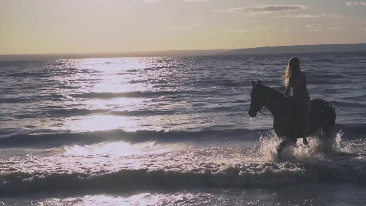 Young sexy woman dressed bikini riding on horse in the river water