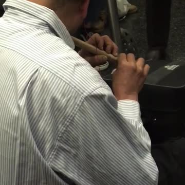Man plays brown flute in subway
