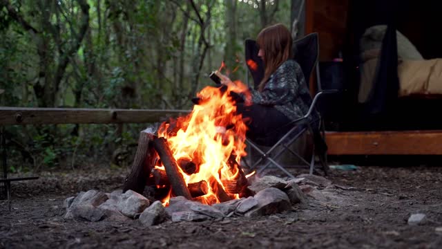 Slow Motion Footage Of A Bonfire With A Woman Reading A Book