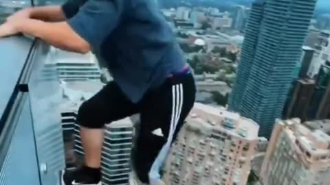 Crazy guy hangs off skyscraper roof