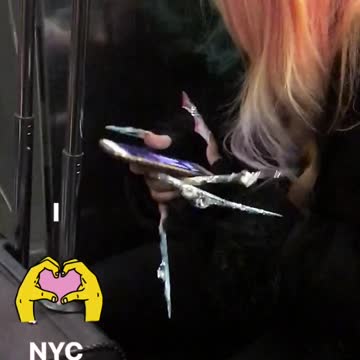 Woman has very long decorated nails on subway train