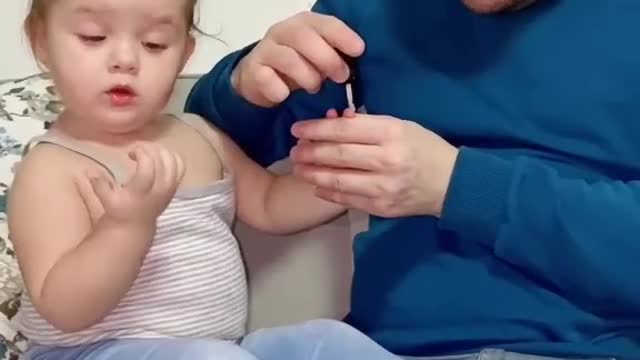 Papa is applying nail paint to his daughter