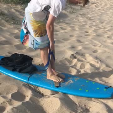 Guy blue surfboard sand beach guy trying to put on underwear windy towel
