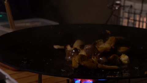 Grilling mushrooms in a pot lid.