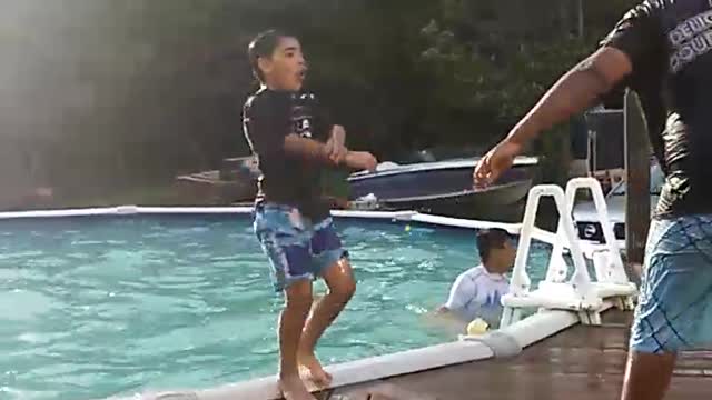 Guy in black shirt pushes kid in pool