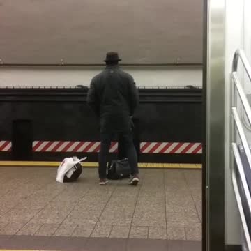 Fedora man does stretches in subway terminal while waiting for 456 train