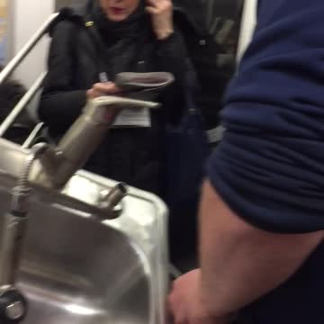 Man has a kitchen sink inside a shopping cart on subway train