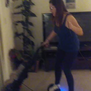 Woman Rides Electric Hoverboard While She Vacuums The House