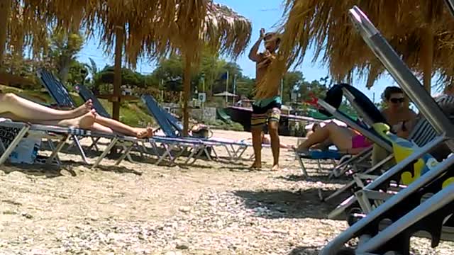 Man in swim shorts dancing by beach chairs