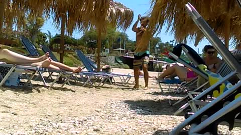 Man in swim shorts dancing by beach chairs