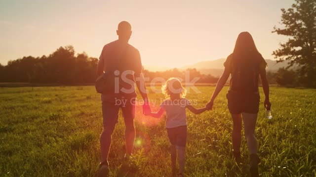 SLO MO TS Family of three hiking across the sunny pasture at sunset stock video