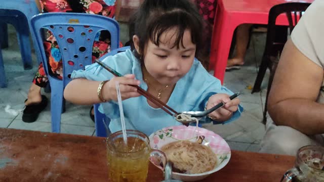 Little girl learns to hold spoon and chopsticks by herself.