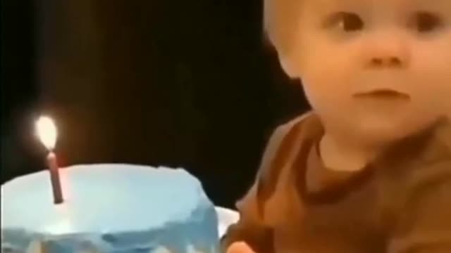 Adorable baby touches lit birthday candle