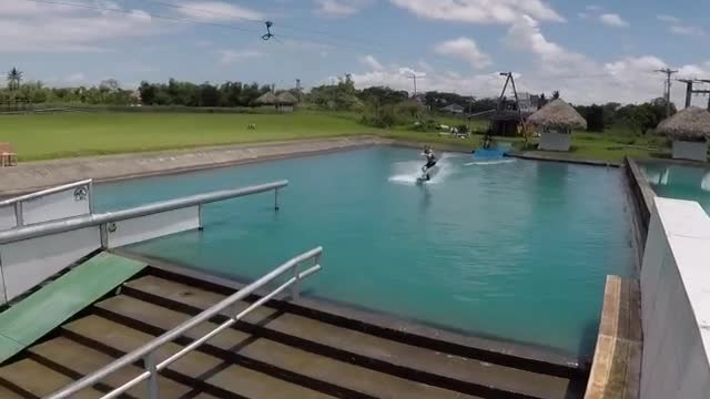 Guy wakeboard obstacle course pulled by rope faceplants off ramp into water