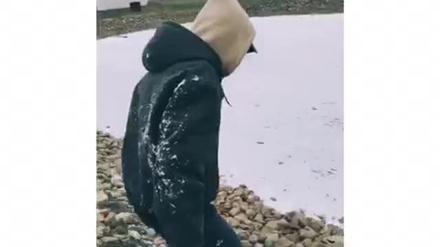 Guy in black jacket with fur slips and slides on frozen lake