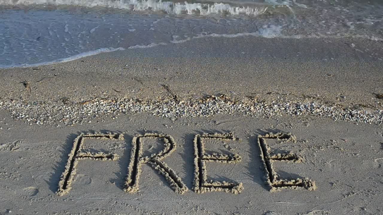 Word "free" written in the sand on a sunny beach