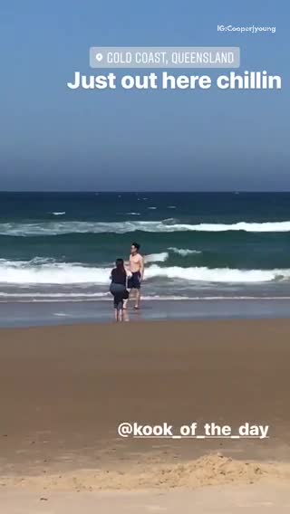 Woman taking pictures of shirtless man on beach