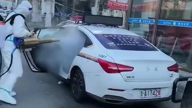 Chinese CCP covid stormtroopers spray a police car