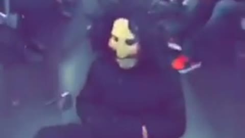 Man sitting in subway floor dressed as doll from saw movies