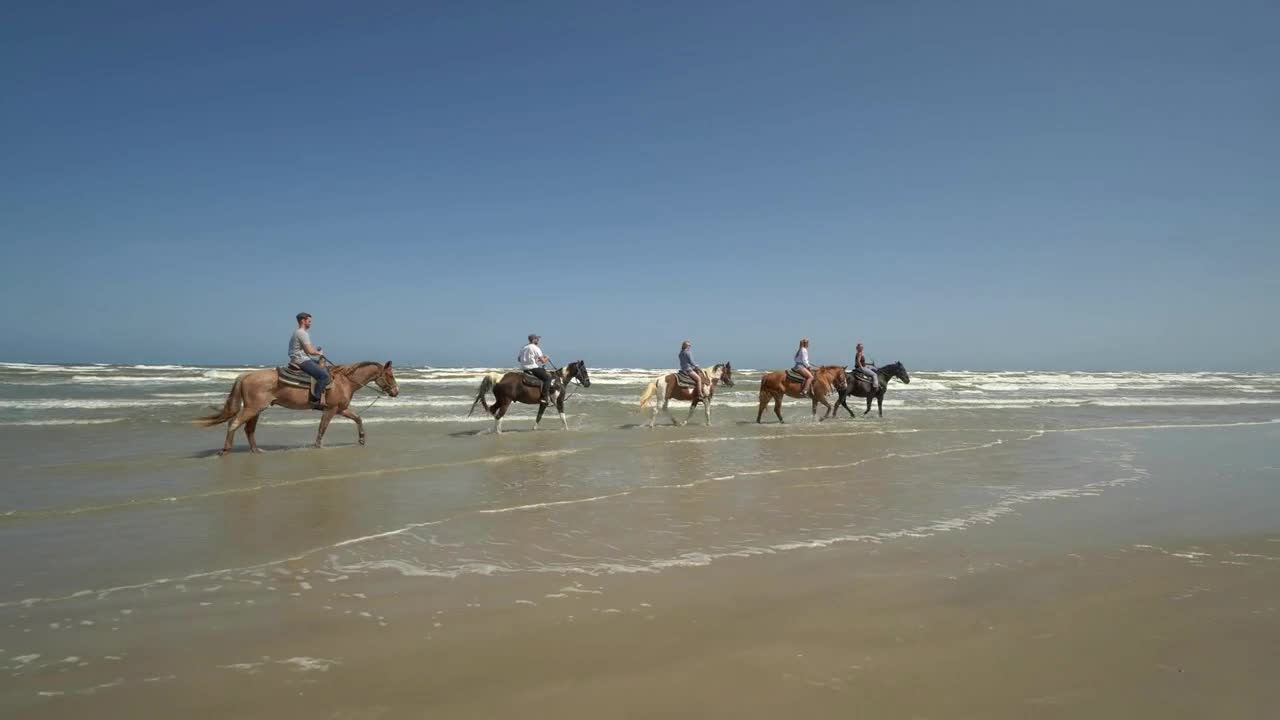 Friends Ride Horses Along Beach