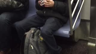 Guy solving white rubik's cube and singing on subway train