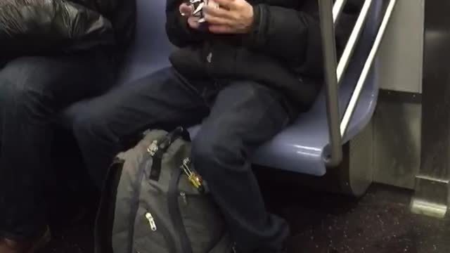 Guy solving white rubik's cube and singing on subway train