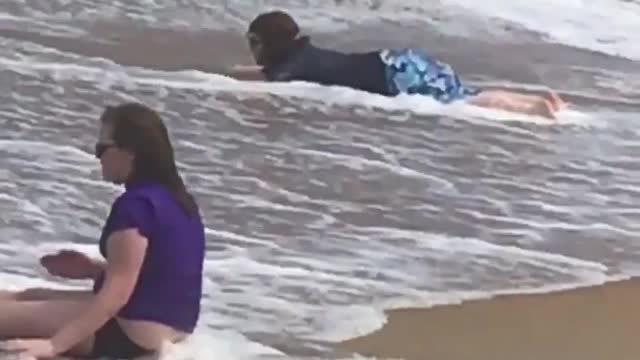 Kid practicing surfing on sand as wave comes in