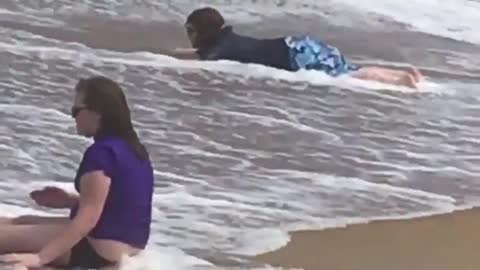 Kid practicing surfing on sand as wave comes in