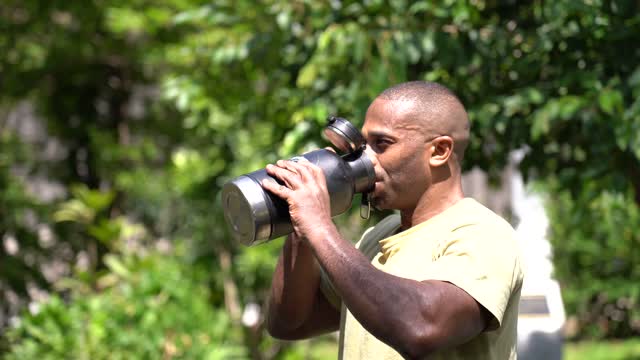 Shallow Focus of Man in Yellow Shirt Drinking From Big Tumbler